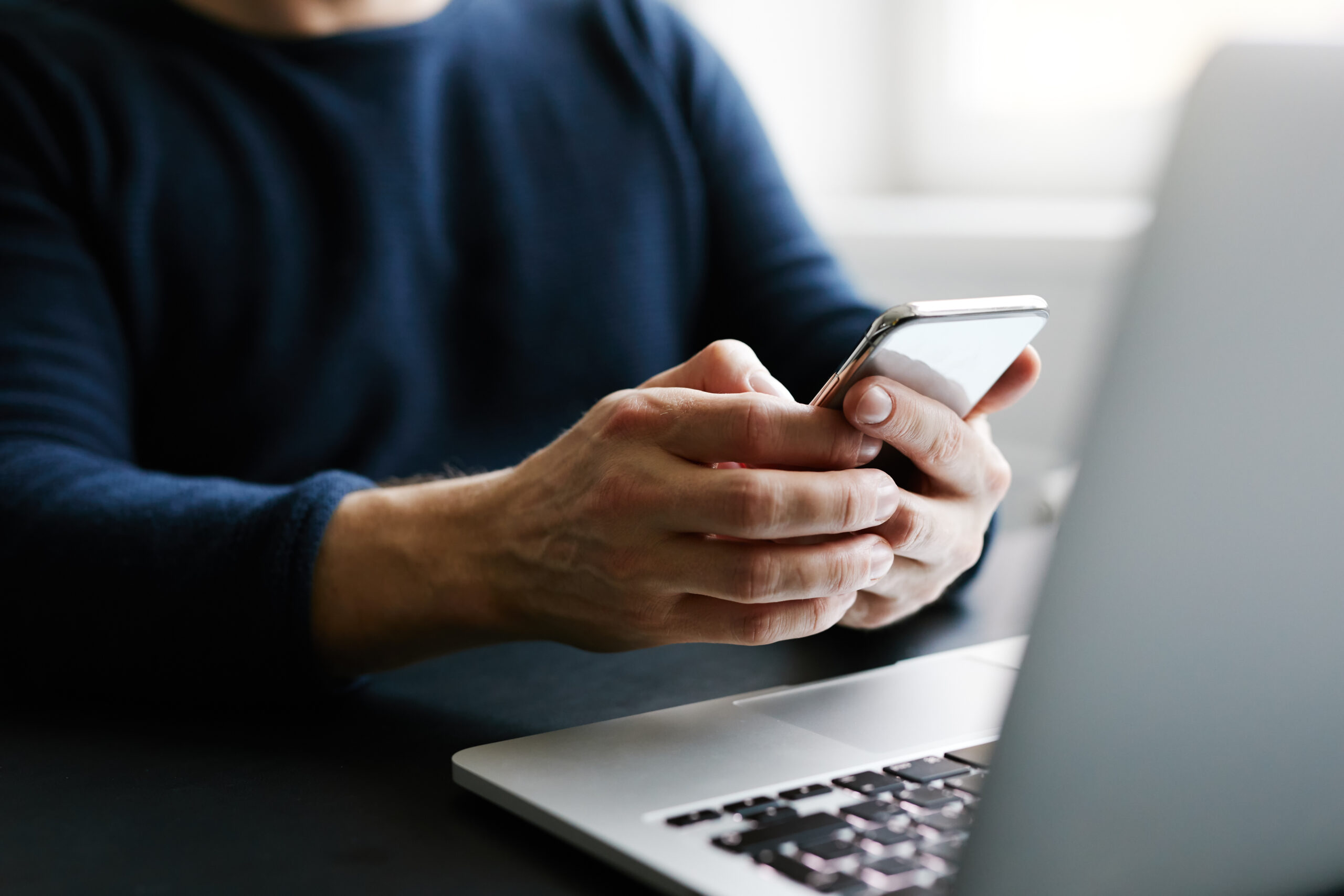 Man with mobile phone and laptop in office using a mobile phone